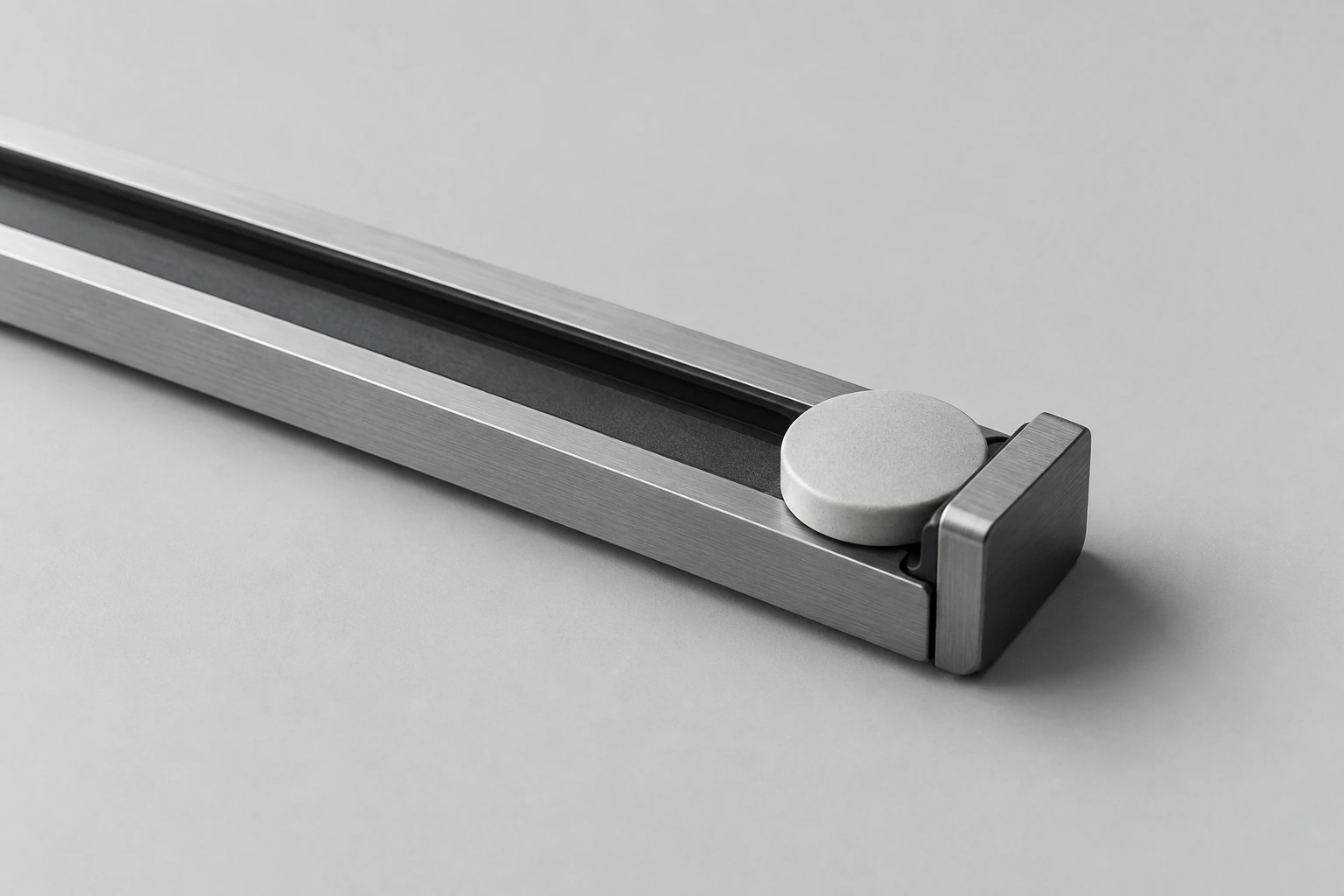 A silver mechanical rail and circular ceramic slider, photographed as an abstract editorial still life.